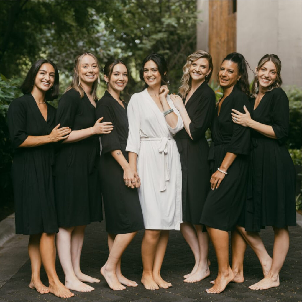 Bride in white robe with bridesmaids before wedding