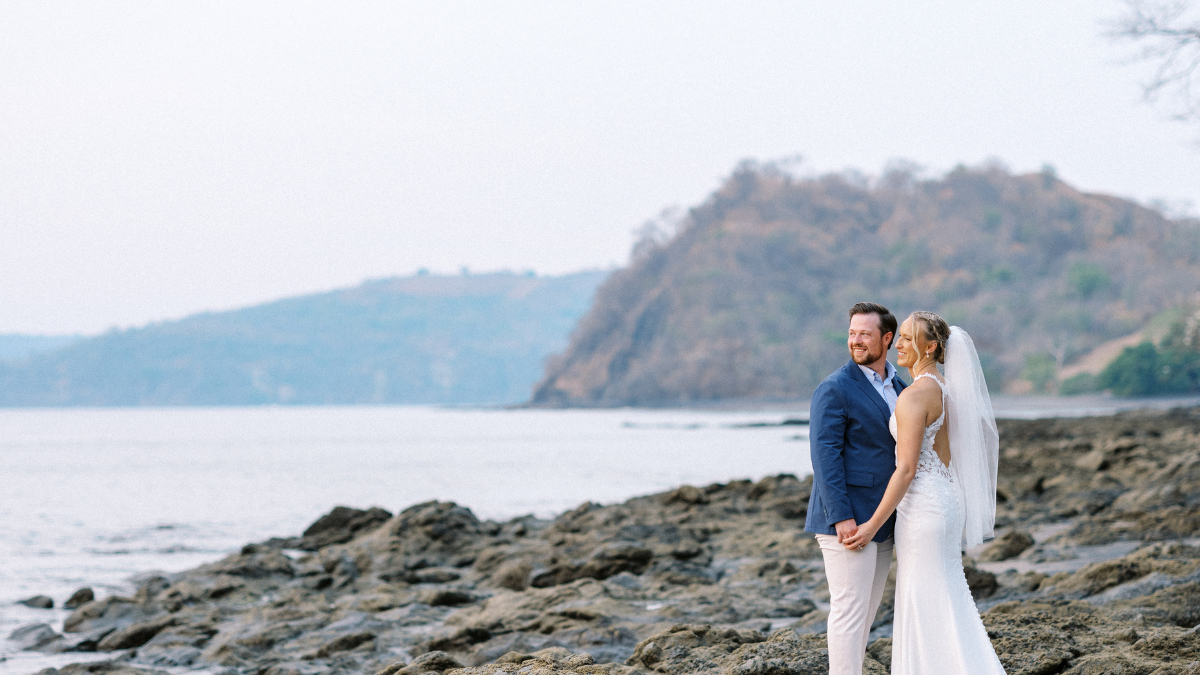 bride and groom standing on rocky beach during costa rica destination wedding
